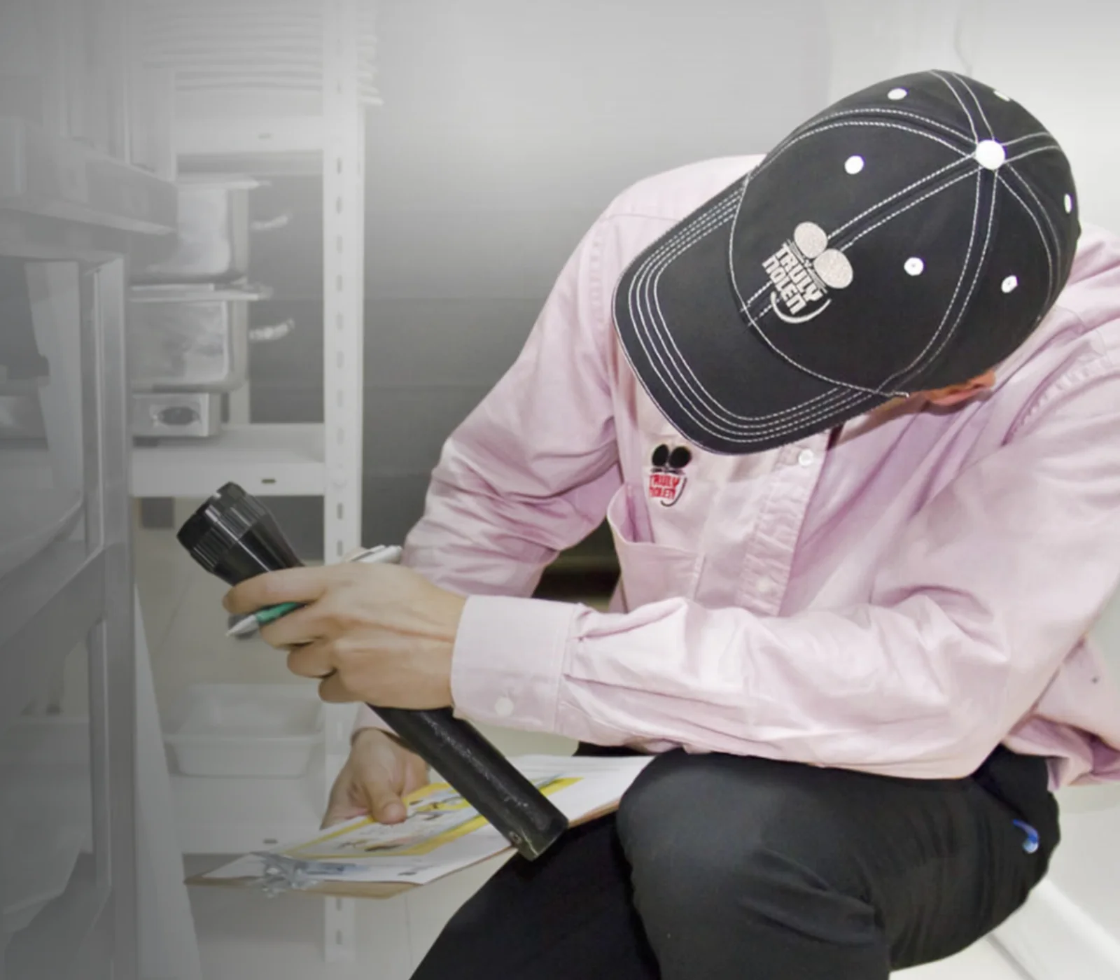 Truly Nolen technician inspecting with a flashlight and recording the findings